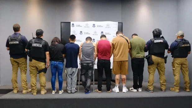 Grupo de personas y agentes de Fiscalía de espaldas durante una presentación oficial.